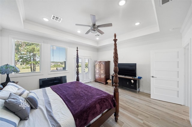 bedroom featuring ceiling fan, light wood-type flooring, a tray ceiling, and ornamental molding