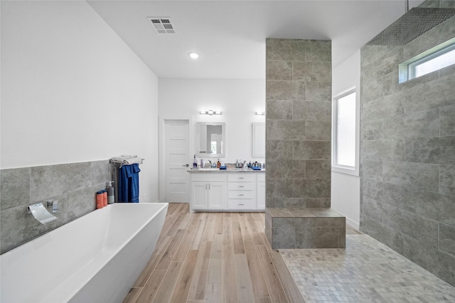 bathroom featuring a washtub, wood-type flooring, vanity, and a healthy amount of sunlight