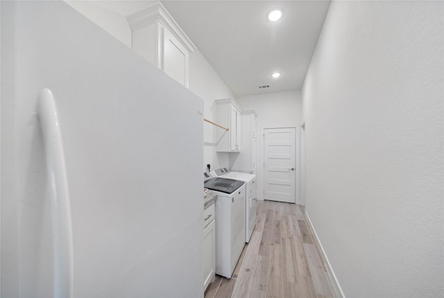 kitchen featuring independent washer and dryer, light wood-type flooring, and white cabinetry