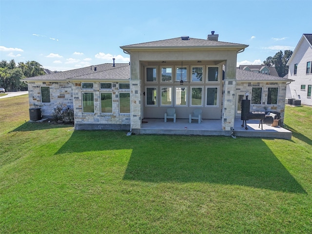 back of property with central air condition unit, a patio area, and a yard