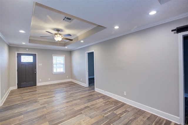 foyer entrance featuring ceiling fan, hardwood / wood-style floors, a tray ceiling, and ornamental molding