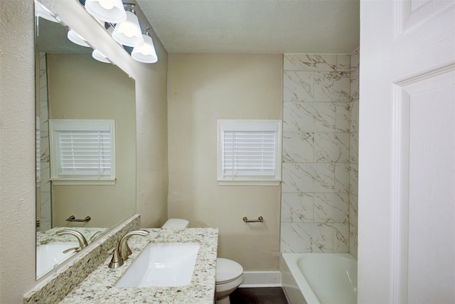 full bathroom featuring toilet, tiled shower / bath, and vanity