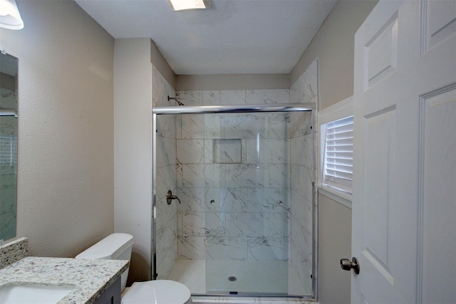 bathroom with walk in shower, vanity, and toilet