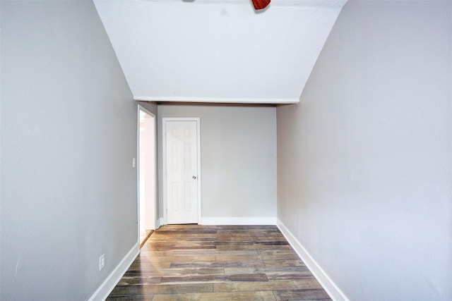 hallway with dark wood-type flooring and lofted ceiling