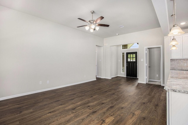 unfurnished living room featuring ceiling fan and dark wood-type flooring