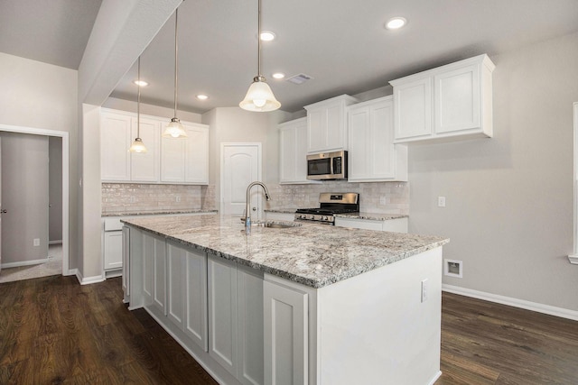 kitchen featuring hanging light fixtures, appliances with stainless steel finishes, sink, white cabinets, and a kitchen island with sink