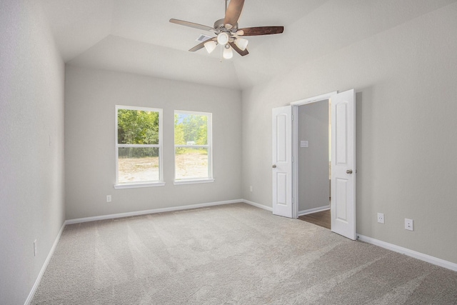 carpeted spare room featuring vaulted ceiling and ceiling fan