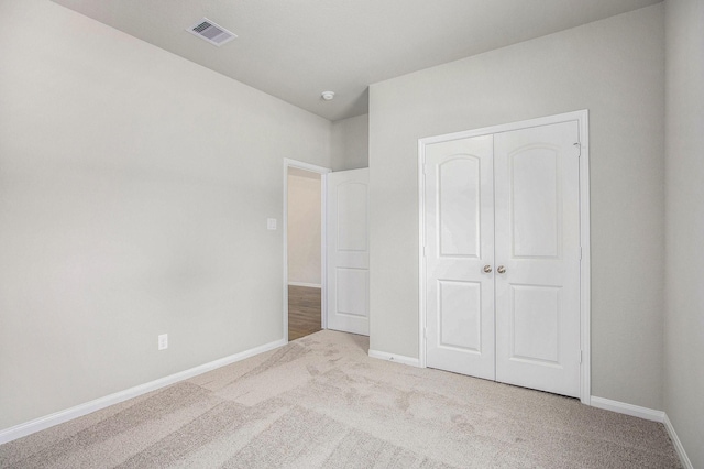 unfurnished bedroom featuring a closet and light carpet