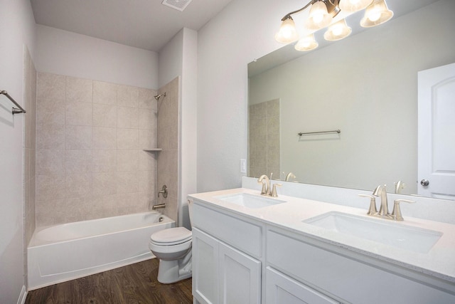 full bathroom featuring hardwood / wood-style flooring, tiled shower / bath combo, vanity, and toilet