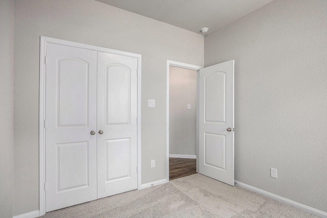 unfurnished bedroom with light colored carpet and a closet