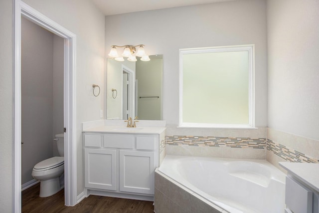 bathroom with wood-type flooring, tiled tub, toilet, and vanity