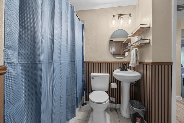 bathroom featuring a textured ceiling, tile patterned floors, a shower with curtain, sink, and toilet