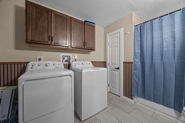 washroom featuring washer and clothes dryer, a textured ceiling, light tile patterned floors, and cabinets