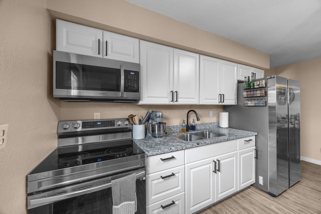 kitchen featuring light hardwood / wood-style floors, light stone countertops, appliances with stainless steel finishes, sink, and white cabinets