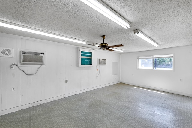 empty room with a textured ceiling, a wall mounted air conditioner, wooden walls, and ceiling fan