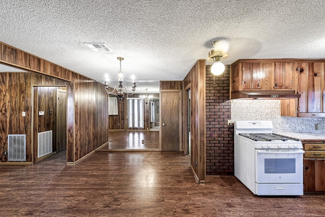 kitchen featuring hanging light fixtures, white gas stove, dark hardwood / wood-style floors, wood walls, and a chandelier