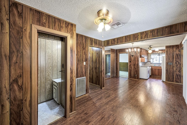 interior space with ceiling fan, a textured ceiling, dark hardwood / wood-style floors, and wooden walls