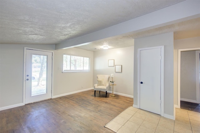 unfurnished room featuring light hardwood / wood-style floors, a textured ceiling, and lofted ceiling