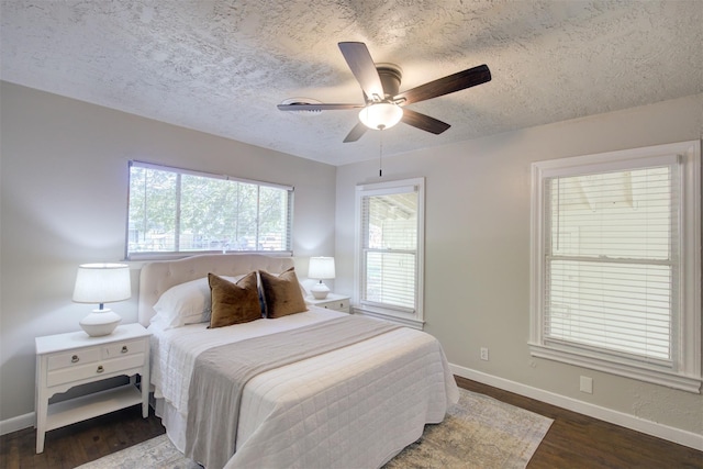 bedroom with ceiling fan, dark wood-type flooring, and a textured ceiling