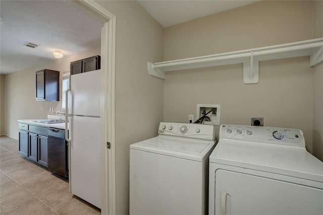 clothes washing area with sink, light tile patterned floors, and separate washer and dryer