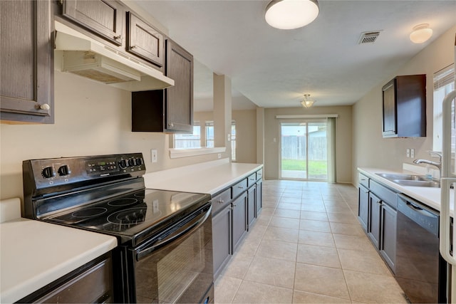 kitchen featuring light tile patterned flooring, black appliances, dark brown cabinets, and a wealth of natural light