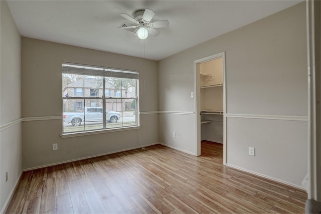 unfurnished bedroom with ceiling fan, light hardwood / wood-style floors, a closet, and a walk in closet