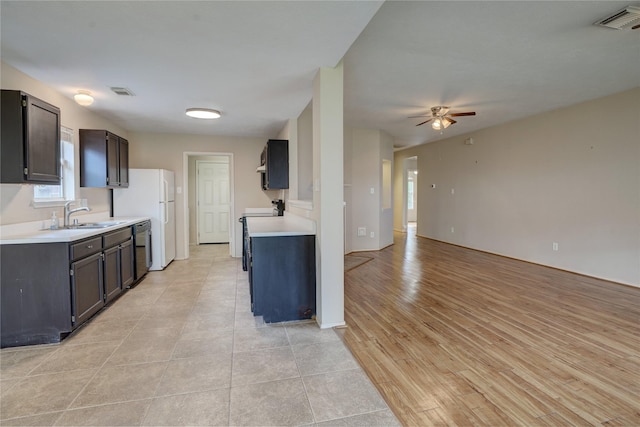 kitchen with stove, stainless steel dishwasher, sink, dark brown cabinets, and ceiling fan