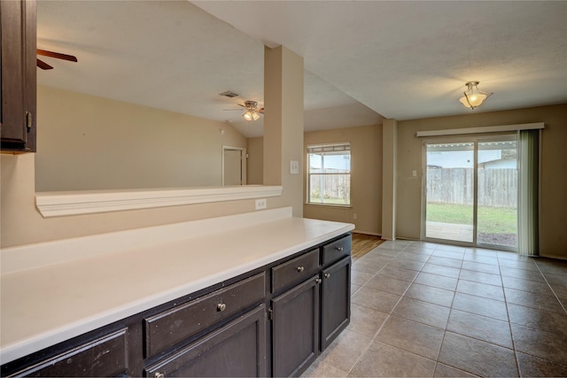 kitchen with dark brown cabinets, ceiling fan, light tile patterned floors, and lofted ceiling