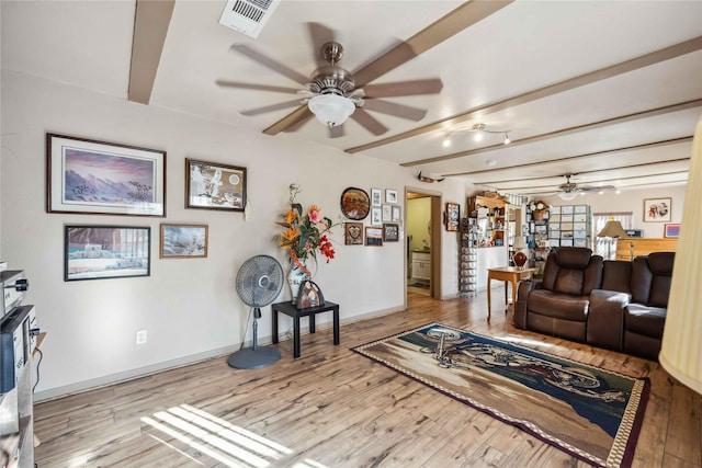 living room featuring light wood-type flooring, ceiling fan, and beam ceiling