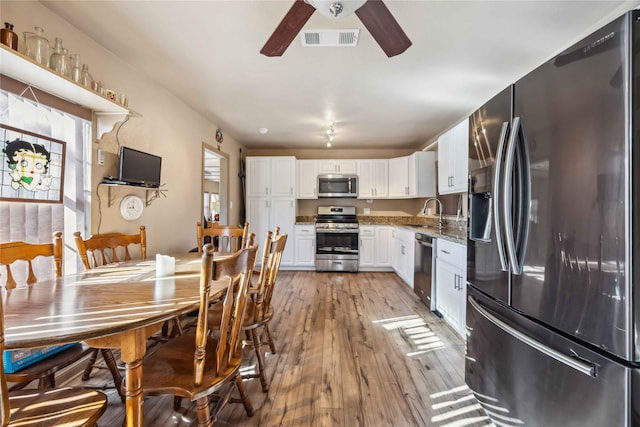 kitchen with white cabinets, sink, light hardwood / wood-style flooring, stainless steel appliances, and light stone counters