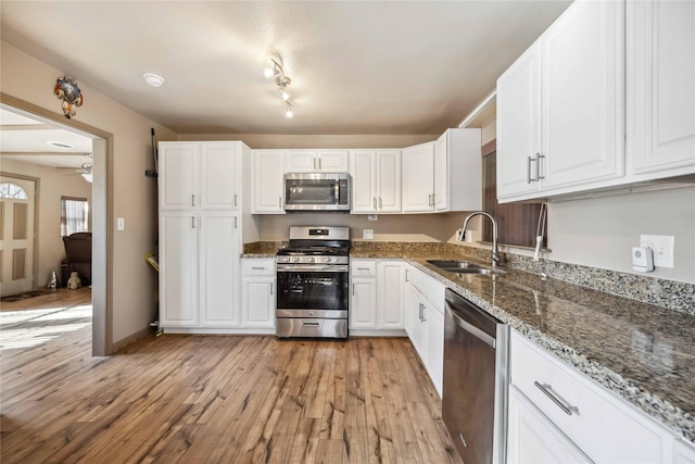 kitchen with sink, white cabinetry, dark stone counters, and stainless steel appliances