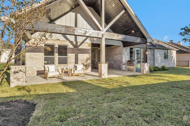 back of property with a lawn, an outdoor kitchen, and a patio