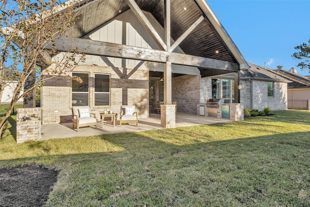 back of property featuring a yard, a patio, and an outdoor kitchen