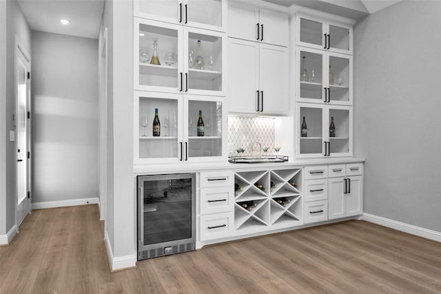 bar featuring light hardwood / wood-style floors, white cabinetry, wine cooler, and tasteful backsplash