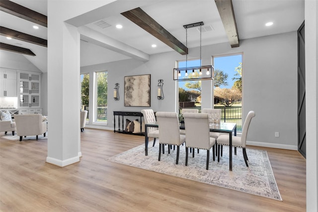 dining space with a notable chandelier, light hardwood / wood-style flooring, and beamed ceiling