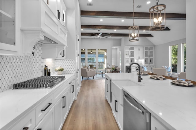 kitchen with white cabinets, appliances with stainless steel finishes, beamed ceiling, sink, and hanging light fixtures