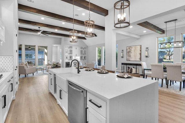 kitchen with pendant lighting, dishwasher, a kitchen island with sink, white cabinetry, and light hardwood / wood-style floors