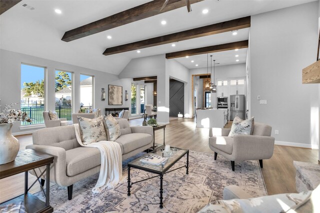 living room with light hardwood / wood-style floors, lofted ceiling with beams, and an inviting chandelier