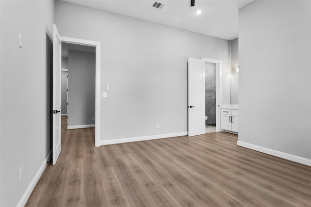 unfurnished bedroom featuring light wood-type flooring and ensuite bath