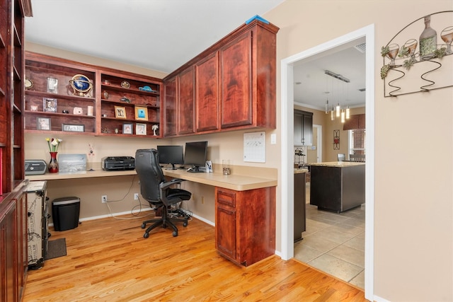 home office with built in desk and light hardwood / wood-style floors