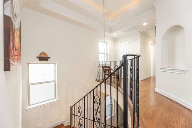 hall featuring a raised ceiling, crown molding, and wood-type flooring