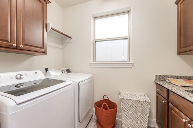 clothes washing area with washing machine and clothes dryer and cabinets