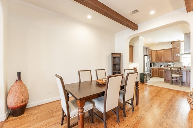 dining space featuring ornamental molding, beam ceiling, and light hardwood / wood-style floors