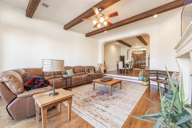 living room with light hardwood / wood-style floors, ceiling fan, and beamed ceiling