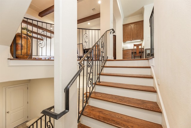 stairs featuring ornamental molding and beam ceiling