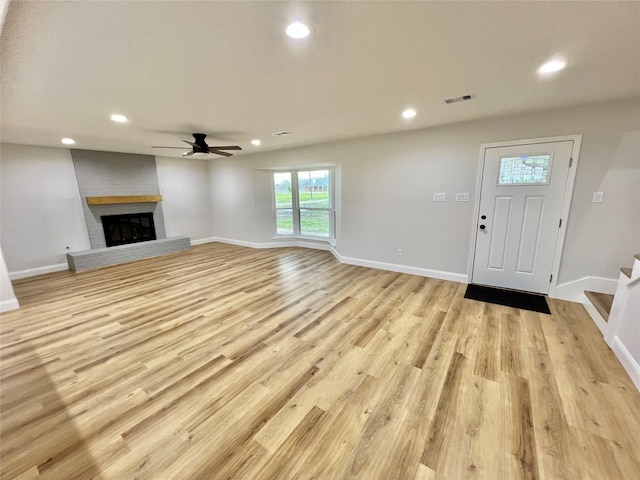 unfurnished living room featuring a fireplace, light hardwood / wood-style floors, and ceiling fan