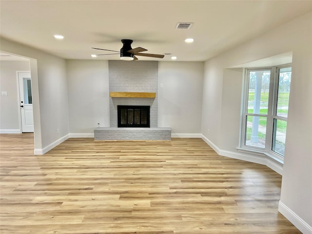 unfurnished living room with light wood-type flooring, ceiling fan, a healthy amount of sunlight, and a fireplace