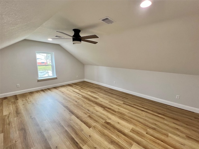 bonus room with ceiling fan, a textured ceiling, vaulted ceiling, and light wood-type flooring