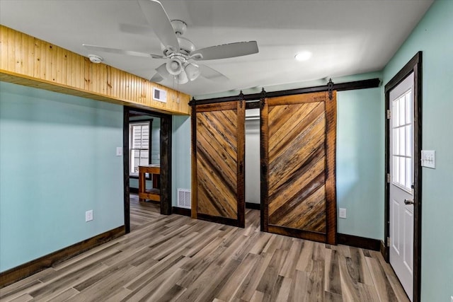 spare room featuring hardwood / wood-style flooring, ceiling fan, and a barn door