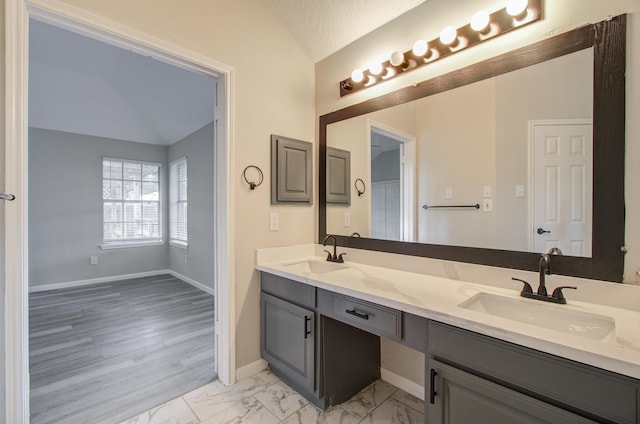 bathroom with a textured ceiling, vanity, and lofted ceiling